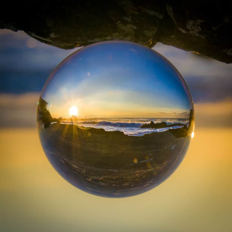 a coastal sunrise through a glass sphere