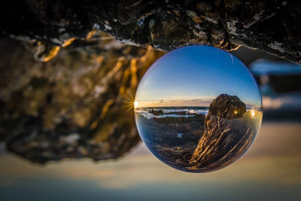 Rockt coast at dawn seen refracted through a glass sphere